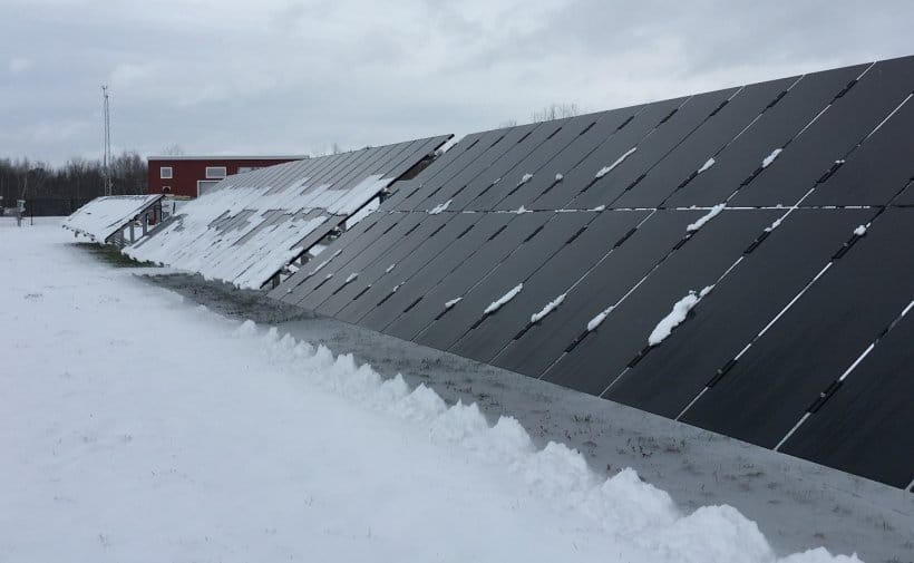Skråmontert solceller på flatt tak under snøvær